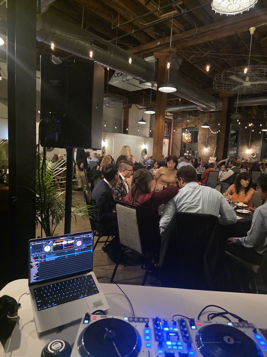 View from DJ Sir Uso's booth during dinner at a St. Louis wedding reception, with the controller and laptop in front of guests at their tables